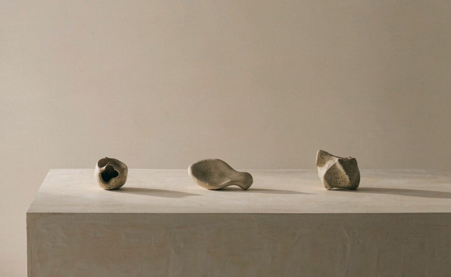 Three small ceramic objects spaced far apart on a pale table